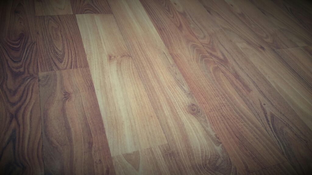 Close-up of a wooden floor showcasing a rich brown grain pattern with a rustic texture.